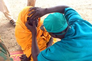 this image is from the "what causes blindness" blog post. It shows an eye-doctor looking for signs of an eye disease or eye infection in a patient from Francophone Africa